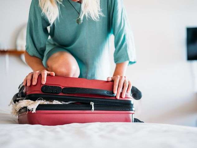 Girl struggling to close suitcase